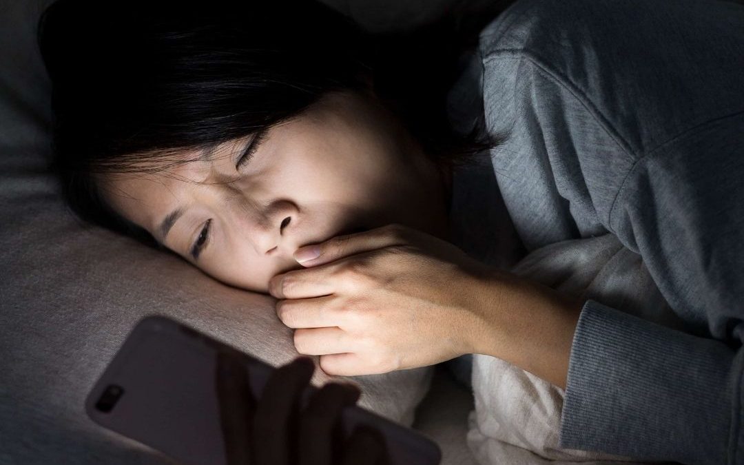 woman tired in bed on phone